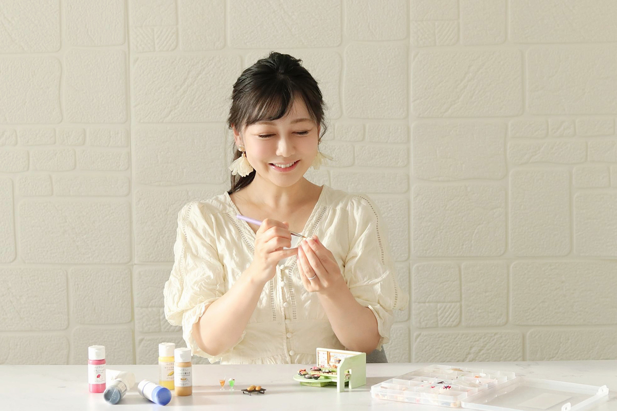 ミニチュアフードを作りながら野津さんがきゅんとした表情をしている写真